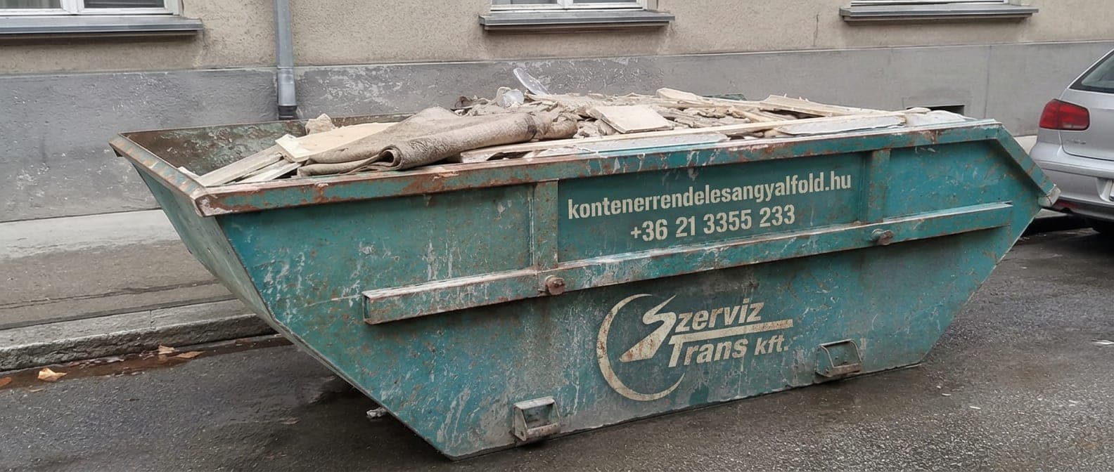 Konténer egy felújítás alatt álló angyalföldi társasház előtt, építési törmelékkel — sittszállítás a XIII. kerületben